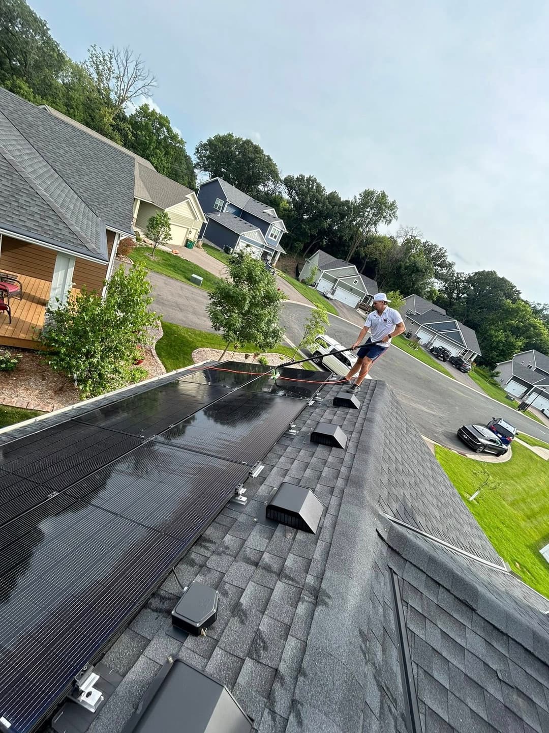 Man installing solar panels on a residential roof in a suburban neighborhood.